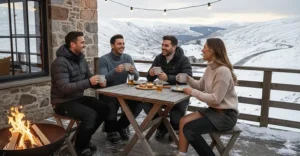 A group of friends sitting outdoors at an apres-ski bar wearing heated trousers to stay warm.