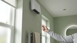 A close-up of a wall-mounted downflow fan heater with a safety pull cord, compliant with UK electrical building regulations.