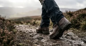 A hiker adjusting their gaiters over waterproof boots and heated socks on a misty, damp winter morning in the UK.