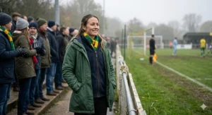 A woman staying warm in a heated thermal base layer while watching a football match in the autumn drizzle.