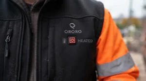 Close-up of a heated jacket control panel showing long battery life settings for outdoor work.