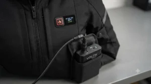 Close-up of a rechargeable lithium battery and temperature control button on a heated motorcycle jacket.