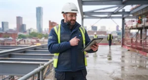 Construction worker staying warm on a British building site wearing a heavy-duty heated FR jacket.