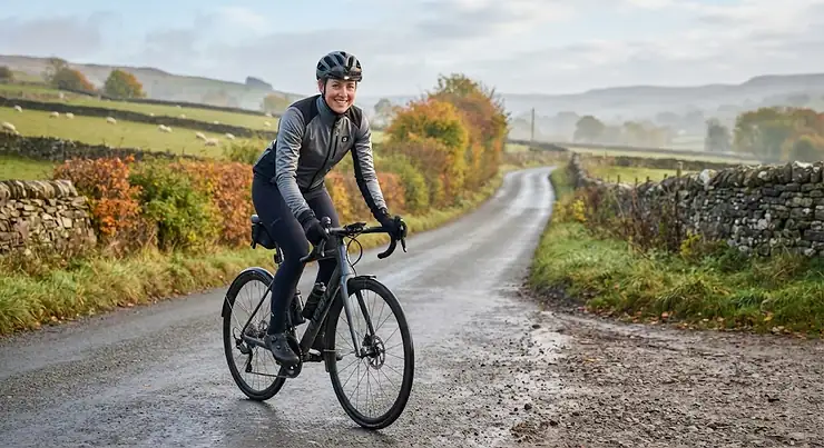Cyclist wearing a warm heated cycling jacket riding on a British country road on a chilly morning heated cycling jacket