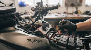 Hands wiring heated grips to a motorcycle battery during a DIY garage installation.