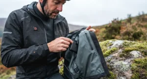 Compact lithium-ion power bank being plugged into the internal power cable of a heated cycling jacket.