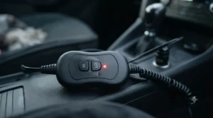 Hand holding a digital temperature controller with adjustable heat settings plugged into a 12V car cigarette lighter socket.