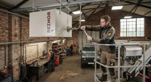 Professional installation of a ceiling-mounted gas space heater in an industrial workshop setting.