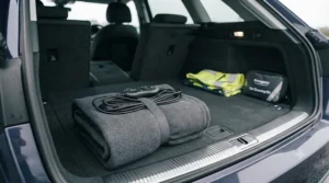 A compact, folded 12V heated travel blanket stored neatly in a car boot ready for a journey.