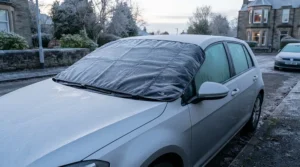 Using a windscreen cover for overnight parking as a smart alternative to harsh metal scrapers on a frosty car window.